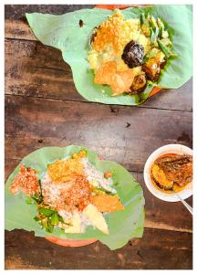 two plates of food on green leaves on a wooden table at Casa Araliya in Negombo