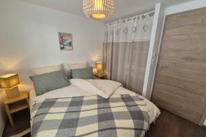 ein Schlafzimmer mit einem Bett mit einer karierten Decke in der Unterkunft Magnifique appartement vue mont blanc in Les Déserts