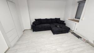 a living room with a black couch in a white room at Garsoniera in Craiova +1 photo