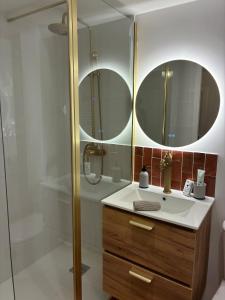 a bathroom with a sink and two mirrors at Appartement chic & cosy - 6 couchages Angers in Angers