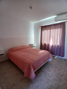 een slaapkamer met een bed met een rode sprei en een raam bij DUPLEX BV in Bell Ville