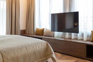 a bedroom with a flat screen tv on a cabinet at Hôtel des Innovations in Marly