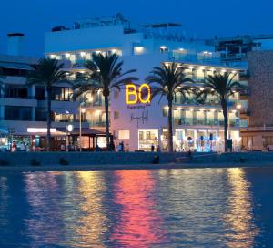 a building with palm trees in front of a body of water at BQ Aguamarina Boutique Hotel in Can Pastilla