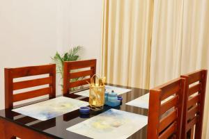 a dining room table with two chairs and a bottle on it at PALM GROVE By D2V in Cochin