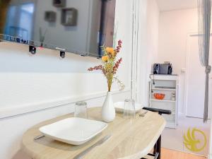 a table with a white vase and flowers on it at Le Spacieux, Gare et Centre, Idéal Pro in Saint-Quentin