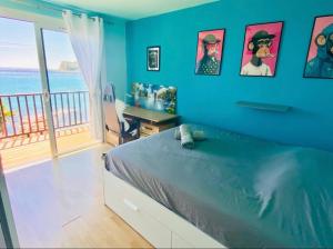 Un dormitorio con una pared azul con una cama y un escritorio. en PARADIS exceptionnel surplombant la MER- accès direct plage/ 8 Pers., en Carry-le-Rouet