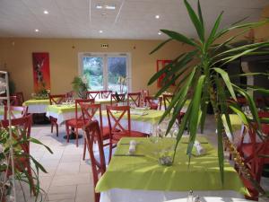 um restaurante com mesas e cadeiras e um vaso de plantas em Hôtel Le Colombier em Saint-Pantaléon-de-Larche