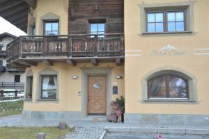 a house with a balcony and a wooden door at Borch Chalet - Exclusive Apartments in Livigno