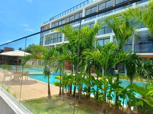 a group of palm trees in front of a building at Aquach Beach Residence in Tamandaré