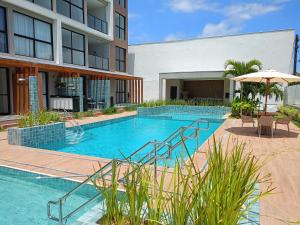 a swimming pool with chairs and an umbrella next to a building at Aquach Beach Residence in Tamandaré