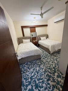 ein Hotelzimmer mit zwei Betten und einem Spiegel in der Unterkunft Luxury 2BR apartment near Muscat Mall in Ma‘ābīlah