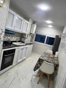 een keuken met witte kasten, een tafel en een wastafel bij Magnifique Studio in Mostaganem