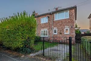 a brick house with a fence and a hedge at Comfy 3Bedroom Manchester Getaway in Manchester