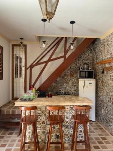 eine Küche mit einer Theke und 3 Barhockern in der Unterkunft Duplex praia de camarupim in Nísia Floresta