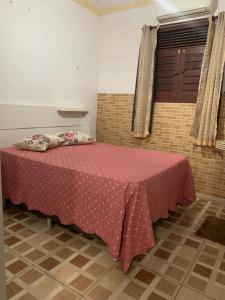 a room with a bed with a pink blanket and a window at Duplex praia de camarupim in Nísia Floresta