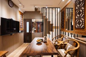 een eetkamer met een houten tafel en een televisie bij Shipu Hotel in Pu-pien