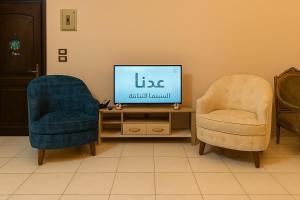 a living room with two chairs and a television at Cairo Airport Oasis Cozy Convenient in Obour