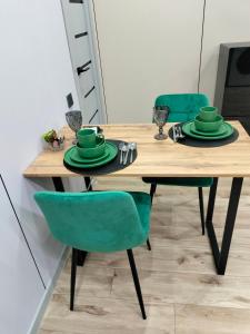 einem Holztisch mit grünen Stühlen und Tellern darauf in der Unterkunft Сейфулина 31 in Balqasch