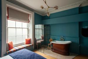 a bathroom with blue walls and a tub and a sink at Lido Townhouse in Bristol