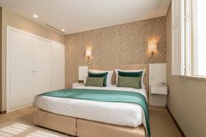 ein Schlafzimmer mit einem großen Bett mit zwei grünen Kissen in der Unterkunft Stella Braga Aparthotel in Braga
