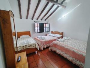 ein Zimmer mit zwei Betten und einem Tisch und einem Fenster in der Unterkunft Casona Antonio Ricaurte in Villa de Leyva