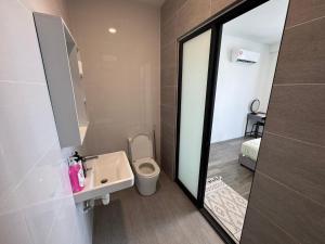 a bathroom with a toilet and a sink and a mirror at Princeton Suite @Kuching Airport in Kuching