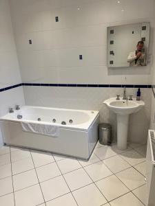 Ein Mann fotografiert ein Badezimmer mit Badewanne und Waschbecken. in der Unterkunft Meadow Farm in Royal Wootton Bassett