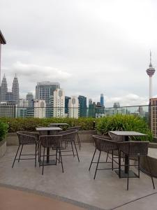 patio con tavoli, sedie e vista sullo skyline della città di Majestic Residence Kuala Lumpur a Kuala Lumpur