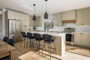 a kitchen with white cabinets and black bar stools at Chalet a Samia - Spa, luxury, Jay Peak view in Mansonville