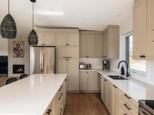 a kitchen with white cabinets and a refrigerator at Chalet a Samia - Spa, luxury, Jay Peak view in Mansonville