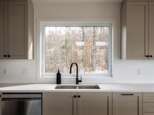 a white kitchen with a sink and a window at Chalet a Samia - Spa, luxury, Jay Peak view in Mansonville
