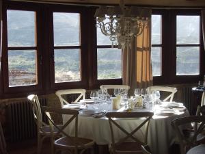 a table with a white table cloth and chairs and windows at Hotel Boutique Real Posada De Liena y Restaurante Liena in Murillo de Gállego