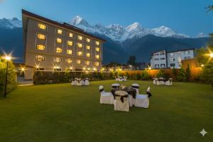 Un hotel con mesas y sillas en un patio con montañas. en Solar Residency, Srinagar, en Srinagar
