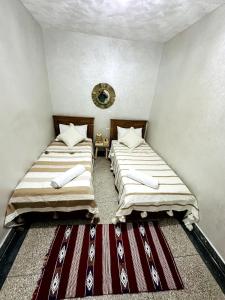 two beds in a small room with a rug at Casa Wavy in Taghazout