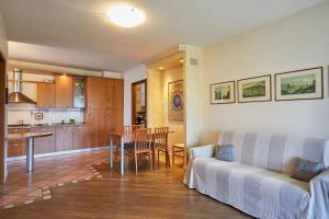 un soggiorno e una cucina con un divano e un tavolo di Platino Apartment - Jacuzzi privata, tre Piscine residenziali ed un bar a 200m dal Lago a Desenzano del Garda