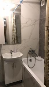 Un baño blanco con lavabo y bañera. en 2к Апартаменты возле ЖД вокзала и Академии 096-55-48-111, en Khmelʼnytsʼkyy