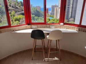 twee stoelen aan een balie in een kamer met ramen bij Rincon de Loix Benidorm in Benidorm