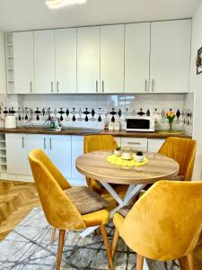 eine Küche mit einem Tisch, Stühlen und einer Mikrowelle in der Unterkunft Apartman KaLux in Vrnjačka Banja