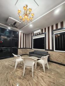 Una sala de estar con una lámpara de araña y una mesa y sillas. en Yashdeep Hotel, en Jāmb