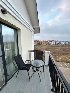 einen Balkon mit einem Tisch und Stühlen sowie Blick auf ein Feld in der Unterkunft Noir Suite in Şelimbăr