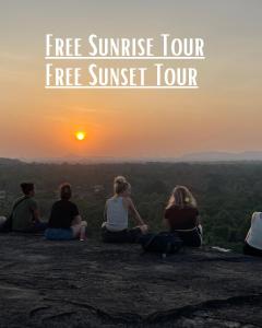 a group of people sitting on a rock watching the sunset at Sigiri Serenity Hostel in Sigiriya