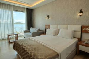 a bedroom with a bed and a chair and a window at Cunda Kivrak Hotel in Ayvalık