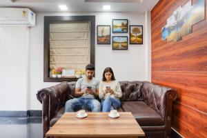 a man and woman sitting on a couch looking at their cell phones at FabHotel SLR Residency - AECS Layout, Brookefield in Bengaluru