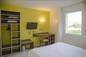 a room with a bed and a desk and a tv at Auberge de la Baie in Ardevon