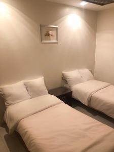 Dos camas en una habitación con sábanas blancas. en Sharty Hotel, en Abu Simbel