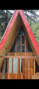 a frame cabin with a red roof and a window at The Cedar Nook Tree House in Jibhi +6 photos