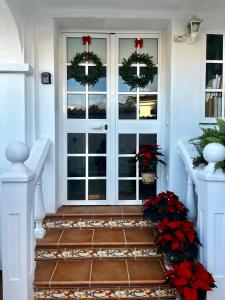 Una puerta de entrada con coronas navideñas y flores de Pascua. en Centro Kennedy, en Algeciras