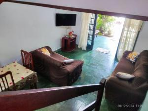 a living room with two couches and a television at Triplex na Prainha in Arraial do Cabo