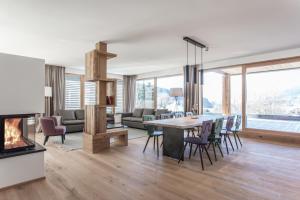 a living room with a dining table and a fireplace at Hubertus Logis Apartments in Brixen im Thale