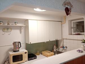 a kitchen with white cabinets and a microwave at Pearl of Danube in Chlʼaba +21 photos